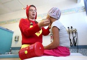 Un médico vestido de superhéroe esculta a una niña con cáncer. EFE/Ulises Ruiz Basurto