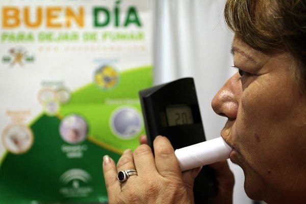 Una mujer sopla por un cooxímetro en un taller para dejar de fumar. Efesalud.com
