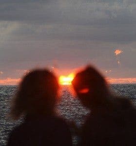Una pareja observa la puesta de sol en una playa. Efesalud.com