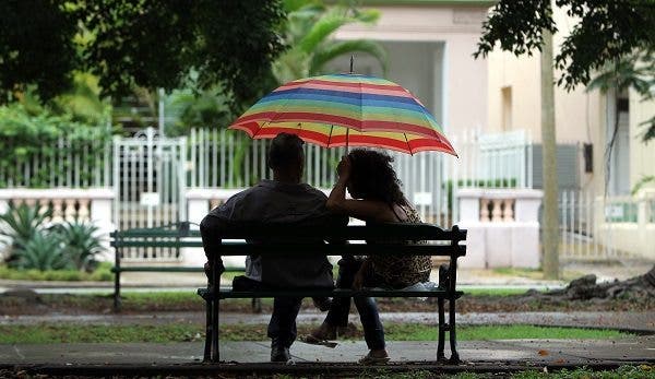 Una pareja conversa bajo la lluvia en el banco de un parque en La Habana (Cuba). Efesalud.com