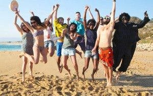 Grupo de 10 jóvenes saltan de alegría en una playa