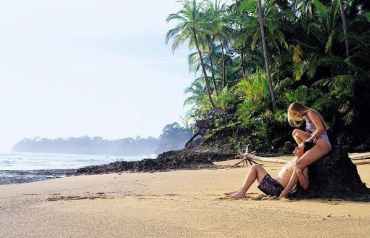 Una pareja abrazada y apoyada en una roca en una playa del Caribe. Efesalud.com