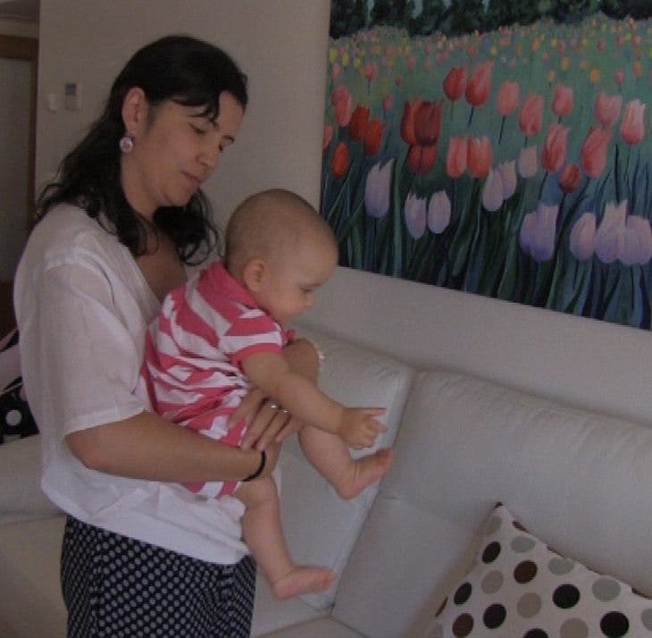 La pediatra María Salmerón observa con detenimiento a su hija, mientras Julia, en brazos de su madre, intenta zafarse para ir al suelo e intentar gatear.