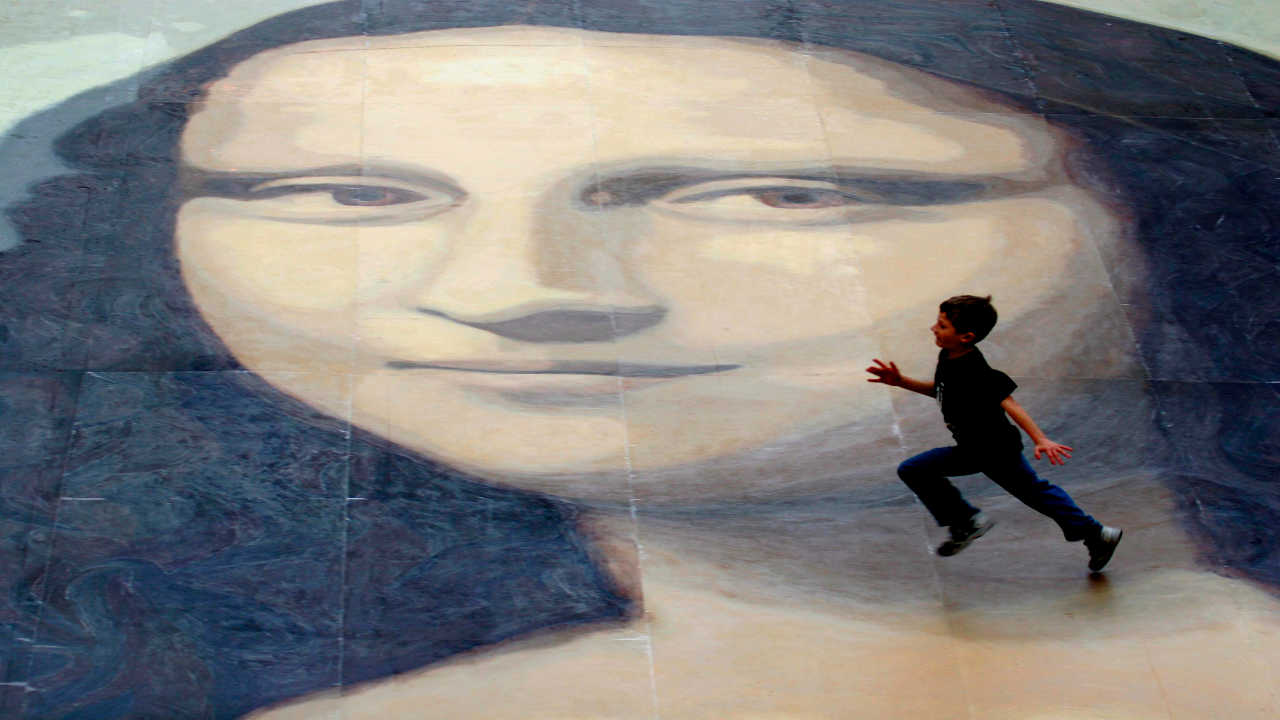 Un niño juega sobre la reproducción de la Mona Lisa valedora del récord Guinness por ser la más grande del mundo, durante su exposición en el centro comercial de Eagles Meadow en Wrexham, Gales.. La versión de la obra de Leonardo da Vinci cubre una superficie de 240 metros cuadrados.