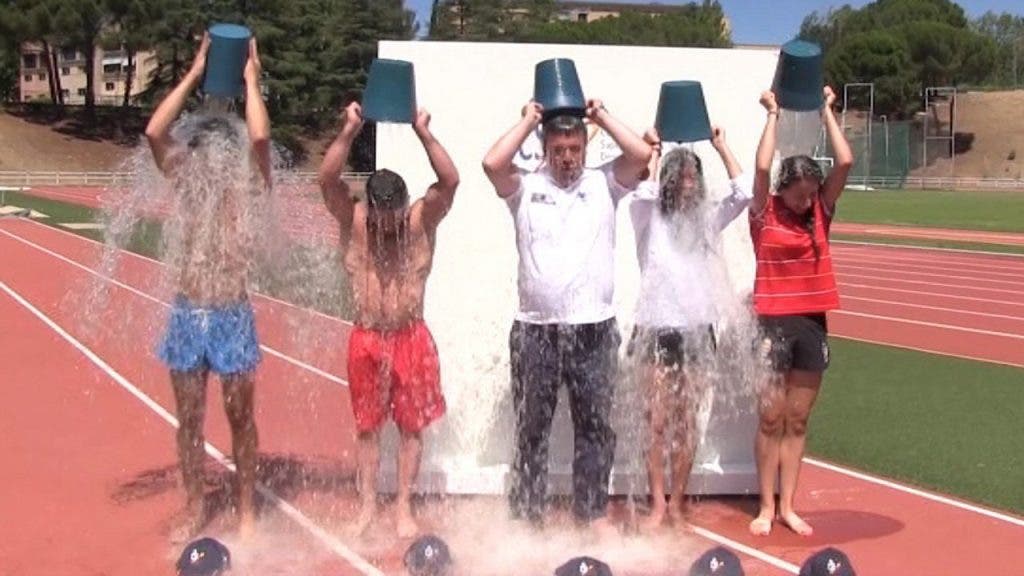El presidente del consejo superior de deportes de España y varios atletas, cinco personas en total se arrojan un cubo de agua helada por encima de sus cabezas.