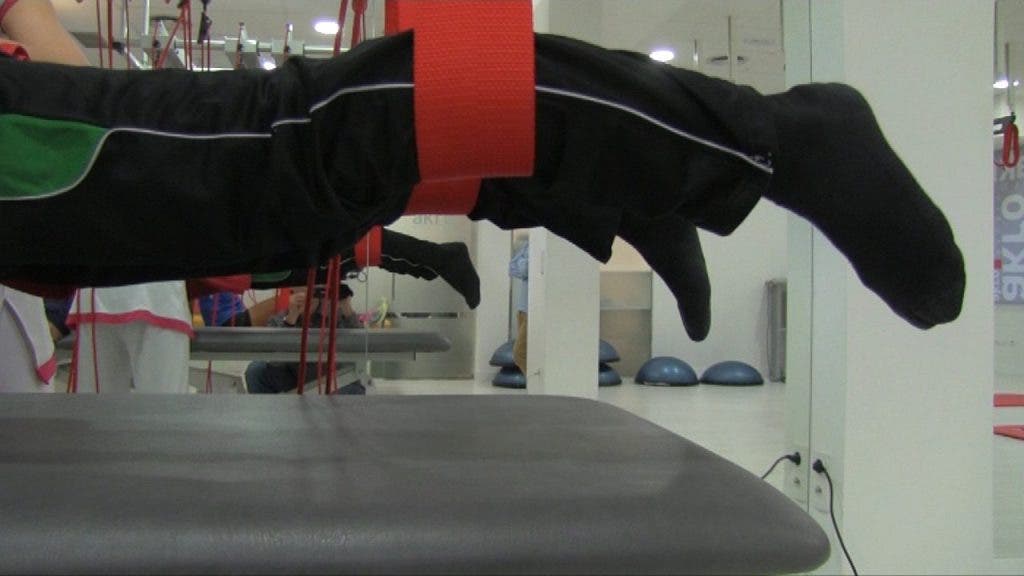Las piernas de un paciente colgadas en el aire de forma horizontal con la técnica Redcord, técnica que usa cuerdas y cinchas para la fisioterapia en suspensión