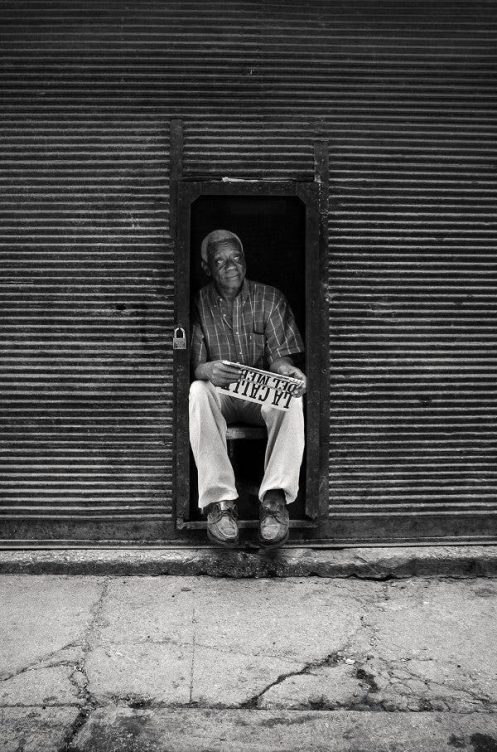 Un hombre mayor sentado en una silla en la puerta de un garaje. Efesalud.com