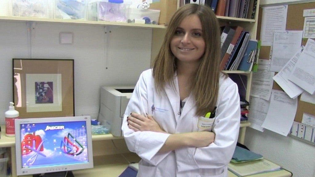 La doctora Tamara Alonso Pérez, neumóloga del Hospital de La Princesa de Madrid, con bata blanca y con su pelo largo y rubio, posa en la consulta de espirometría ofreciéndonos una sonrisa.