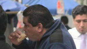 Hombre obeso comiendo una arepa rellena